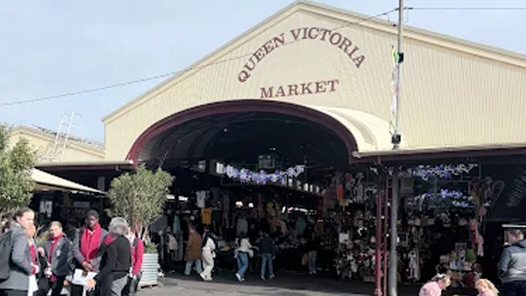 Queen Victoria Market entrance arch with shoppers under the historic sheds, Melbourne