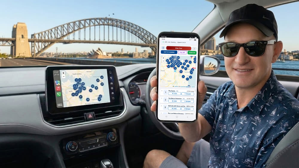 Andrew Sorokin holding a phone running the Sydney self-drive audio tour in a car near the Sydney Harbour Bridge